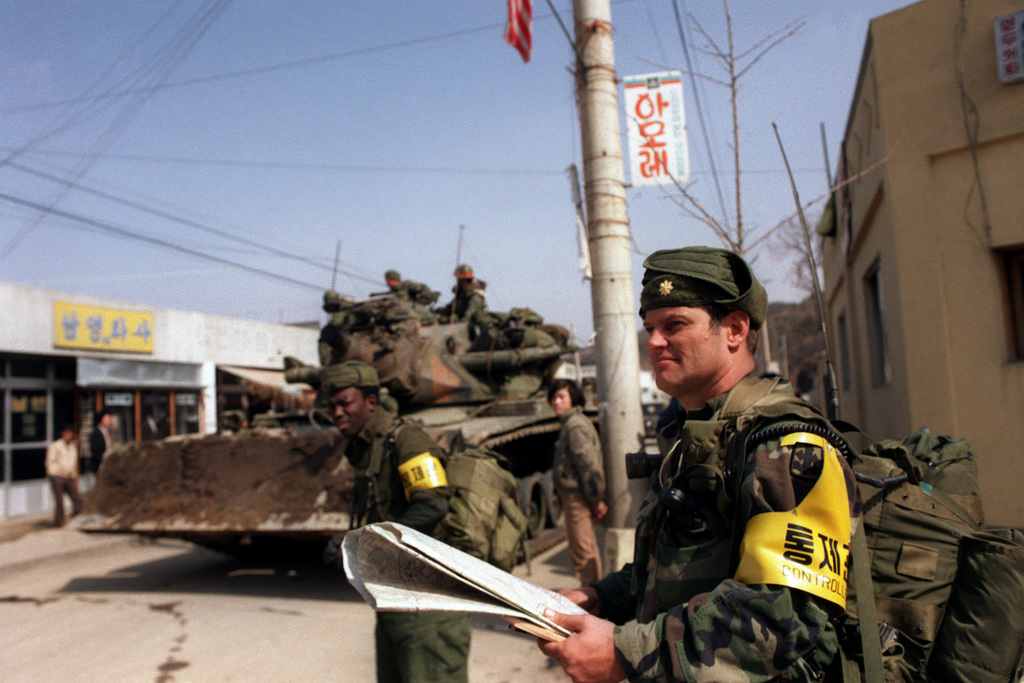Major Edward R. Cruickshank, Commander of the 1st Battalion, 299th Infantry, Hawaii Army National Guard, observes the entry of 25th Infantry Division Orange Forces into the city, as they advance against the Blue Forces during the joint South Korean/US Exercise TEAM SPIRIT ’84. Visible to the left is an M728 combat engineer vehicle.


