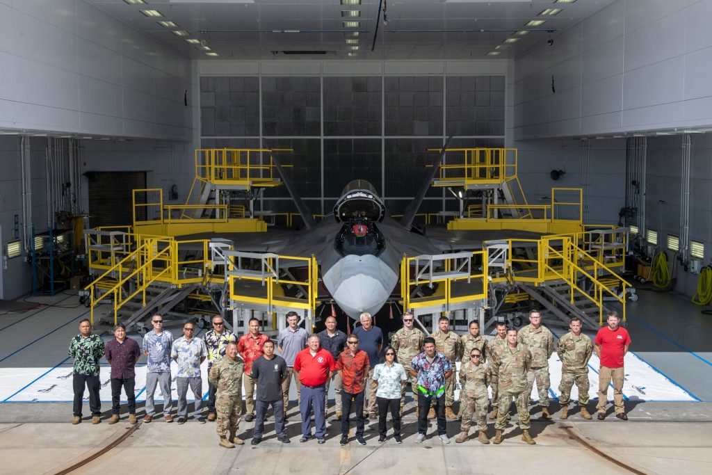 A team comprised of U.S. Air Force, Air National Guard, and contract personnel pose in front of their custom-designed F-22 Raptor maintenance stands during the debut event Sept. 26, 2024, at Joint Base Pearl Harbor-Hickam. The specialized maintenance stands are the culmination of nearly five years of collaboration between Total Force Airmen and the National Guard Bureau, providing a safer and more efficient way to access the hard-to-reach areas of one of the world’s most advanced stealth aircraft. (U.S. Air National Guard photo by Master Sgt. Mysti Bicoy)