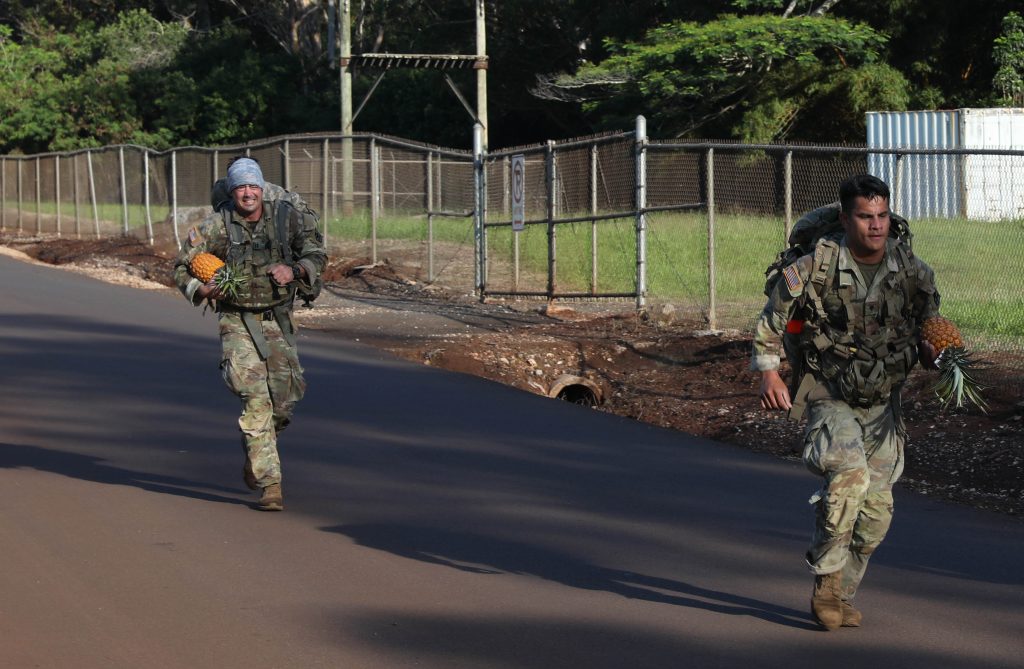 Hawaii Army National Guard Spc. Quinn Mears, left, a combat engineer assigned to Alpha Company, 227th Brigade Engineering Battalion, runs to try and overtake Guam Army National Guard Soldier Spc. Rency Une, a mortarman, assigned to Charlie Company, 1st Battalion, 294th Infantry Regiment during the mystery event of the Region VII annual Best Warrior Competition, Schofield Barracks, Hawaii, May 7-11, 2023. National Guard service members later ate the pineapple they brought back from the ruck march portion of the event. (U.S. Army National Guard photo by Spc. Sean Walker)