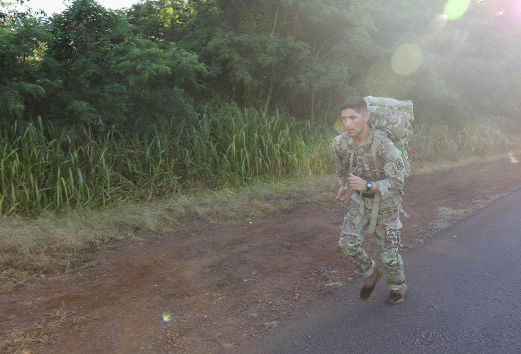 Hawaii Army National Guard Sgt. Cooper Hulse, a cavalry scout assigned to Headquarters and Headquarters Squadron, 1-299th Cavalry Regiment runs with a heavy ruck weighing over 45 lbs. during the Mystery event of the Region VII annual Best Warrior Competition, Schofield Barracks, Hawaii, May 7-11, 2023. For the Mystery event National Guard service members ruck marched for approximately six miles and carried back with them the pineapple mystery item. (U.S. Army National Guard photo by Spc. Sean Walker)