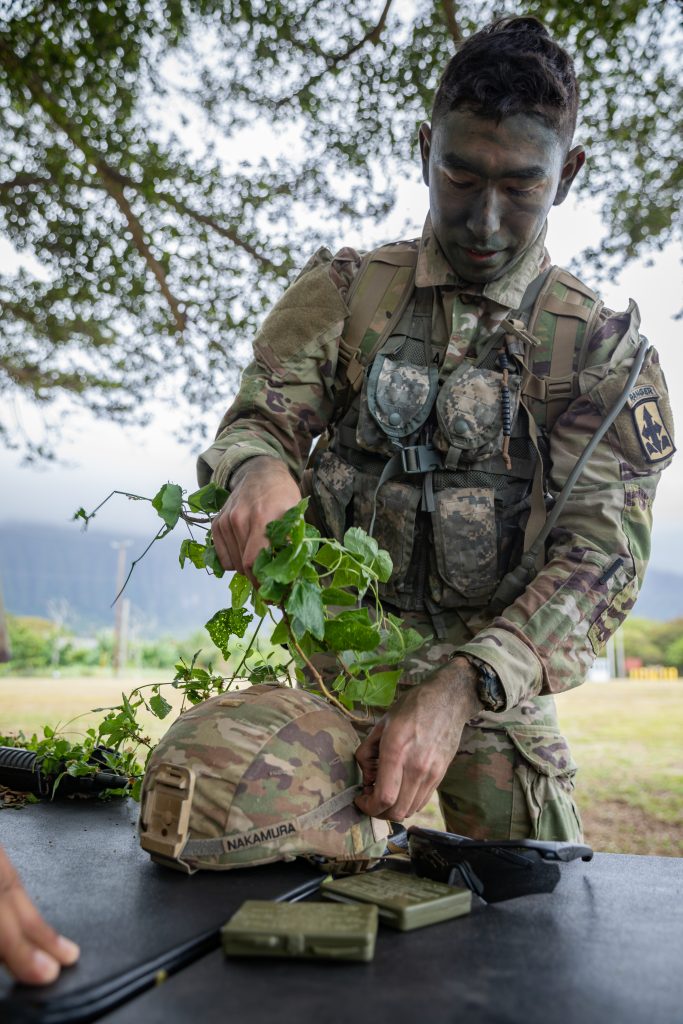 U.S. Army Spc. Andruw Nakamura, an infantryman assigned to Charlie Troop, 1st Squadron, 299th Cavalry Regiment, 9th Infantry Brigade Combat Team, Hawaii Army National Guard (HIARNG) applies camouflage to an advanced combat helmet during the HIARNG 2024 Best Warrior Competition at the Regional Training Institute, Waimanalo, Hawaii, April 5-7, 2024. The Best Warrior Competition is an annual event conducted by the HIARNG to identify the most skilled and proficient Soldiers across various military occupational specialties (MOS). (U.S. Army National Guard photo by Sgt. Lianne M. Hirano)