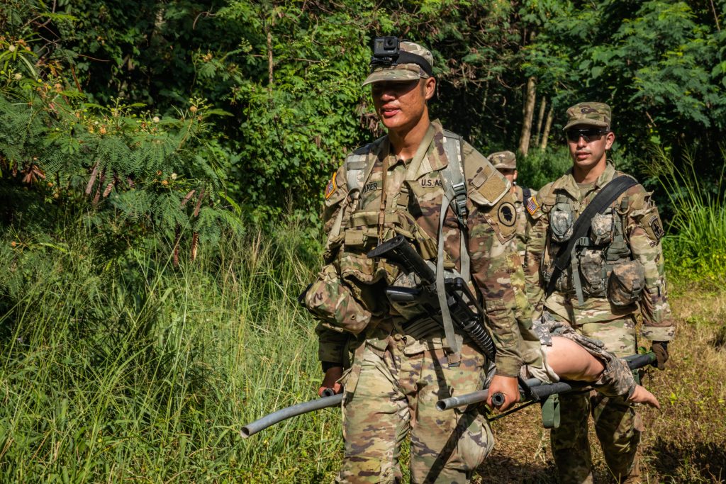 U.S. Army Spc. Sean Walker, left, a mass communications specialist assigned to the 117th Mobile Public Affairs Detachment, 103rd Troop Command, Hawaii Army National Guard (HIARNG), and Spc. Andruw Nakamura, an infantryman assigned to Charlie Troop, 1st Squadron, 299th Cavalry Regiment, 9th Infantry Brigade Combat Team, HIARNG, carry a simulated casualty in the team event during the HIARNG 2024 Best Warrior Competition at the Regional Training Institute, Waimanalo, Hawaii, April 5-7, 2024. The Best Warrior Competition is an annual event conducted by the HIARNG to identify the most skilled and proficient Soldiers across various military occupational specialties (MOS). (U.S. Army National Guard photo by Sgt. Lianne M. Hirano)