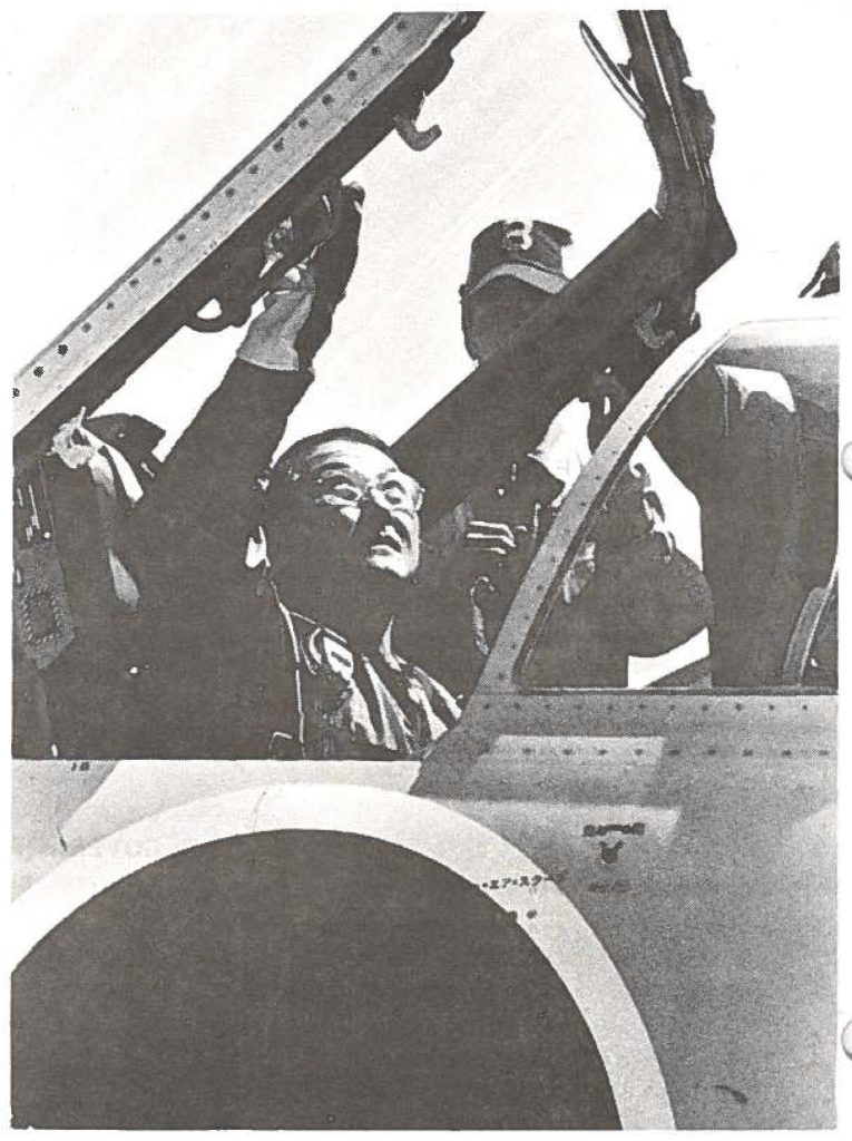 Japanese flight crew members assist Brig. Gen. Arthur U. lshimoto, HANG commander, in buckling up for a flight aboard a Japanese trainer aircraft.