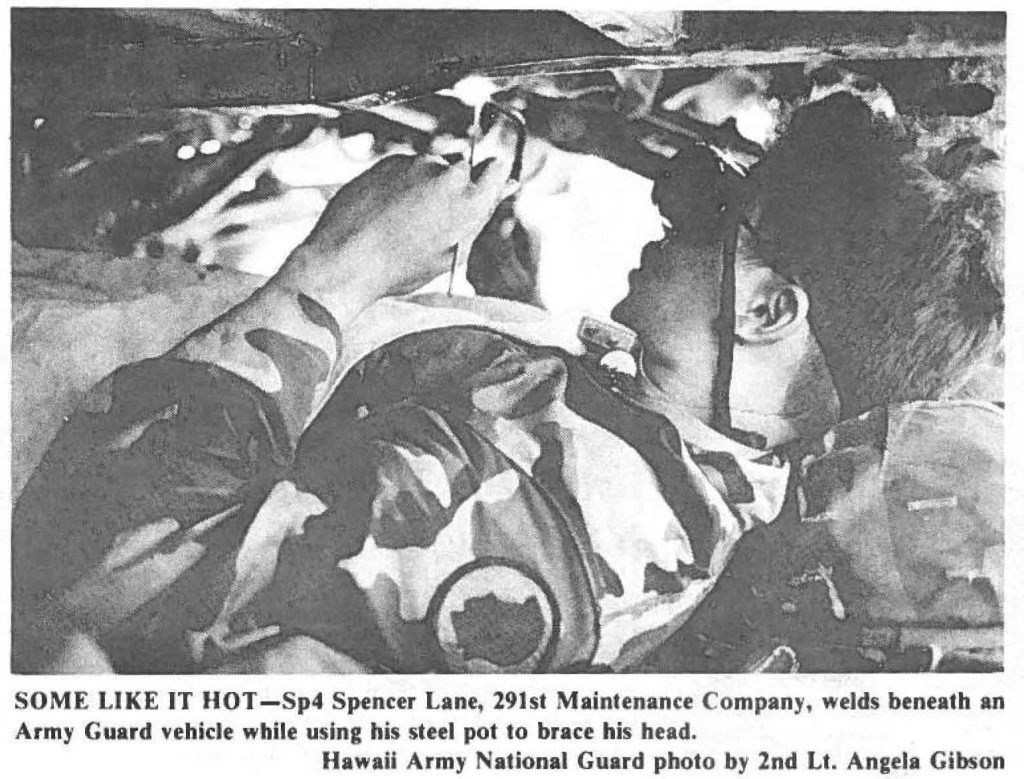 SOME LIKE IT HOT-Sp4 Spencer Lane, 291st Maintenance Company, welds beneath an Army Guard vehicle while using his steel pot to brace his head. Hawaii Army National Guard photo by 2nd Lt. Angela Gibson
