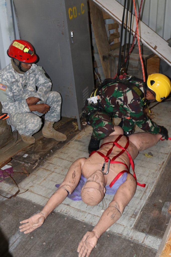 Sgt. Jaypee Pardo, a carpentry and masonry specialist with the 230th Engineer Company and a Search and Extraction team member of the Hawaii Army National Guard's Chemical, Biological, Radiological, Nuclear and High-Yield Explosive, Enhanced Response Force Package (CERFP) team along with a Soldier of the Indonesian National Military - Quick Response Disaster Management Unit secure a casualty in preparation for extraction techniques during a confined space rescue exercise in Kapolei, Hawaii, July 11, 2018. This marks the first joint training exercise between the HIARNG, Philippine and Indonesian CERFP teams. (U.S. Army National Guard Photo by Sgt. Tinisha Mellein-Fortson/Released)