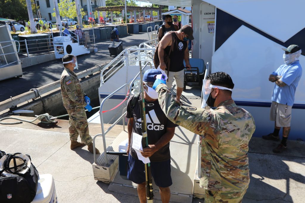 Cpl. Manuel Soco, Carpentry and Masonry Specialist and Spc. Scottie Momoa, Plumber, with the Hawaii Army National Guard, 230th Engineer Company, assigned to Task Force Maui assist community liaisons with temperature screening and crowd control at the harbor in Lahaina, HI, August 21, 2020.