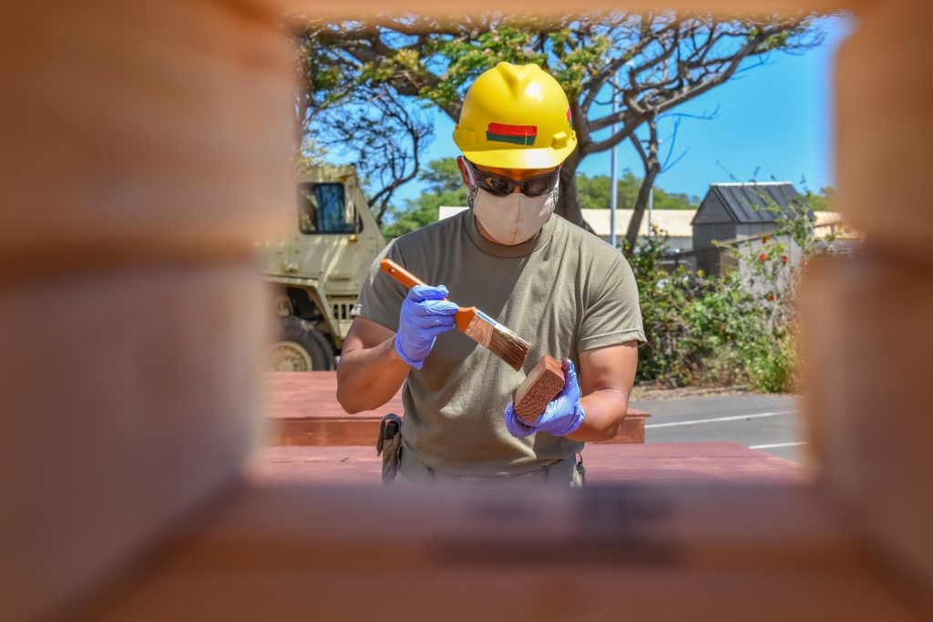 Sgt. Josiah Baisa, Carpentry Sergeant with 230th Engineer Company, 103rd Troop Command, Hawaii Army National Guard utilize his technical skills to apply paint sealer to wooden platforms they've constructed to help Maui county residents affected by the coronavirus during the COVID-19 pandemic, Kahului, Hawaii, June 3, 2020. (U.S. Army National Guard photo by Sgt. 1st Class Theresa Gualdarama)