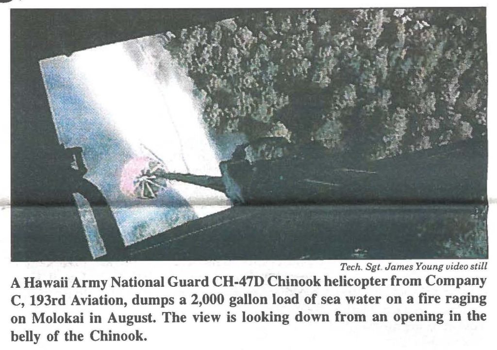 A Hawaii Army National Guard CH-47D Chinook helicopter from Company C, 193rd Aviation, dumps a 2,000 gallon load of sea water on a fire raging on Molokai in August. The view is looking down from an opening in the belly of the Chinook.