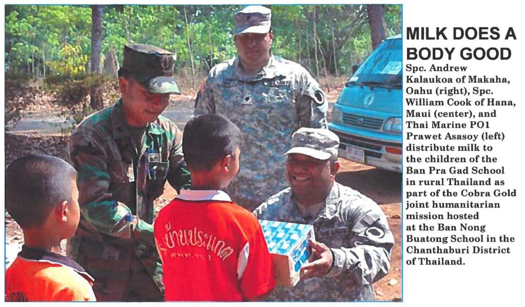 MILK DOES A BODY GOOD Spc. Andrew Kalaukoa of Makaha, Oahu (right), Spc. William Cook of Hana, Maui (center), and Thai Marine POI Prawet Asasoy (left) distribute milk to the children of the Ban Pra Gad School in rural Thailand as part of the Cobra Gold joint humanitarian mission hosted at the Ban Nong Buatong School in the Chanthaburi District of Thailand.