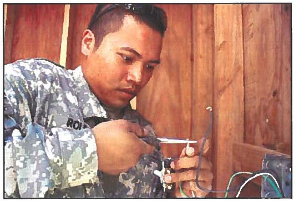 A POSITIVE CONNECTION - Pvt. Eddie Roldan, an electrician from Maui, wires a light switch in the new outhouse.